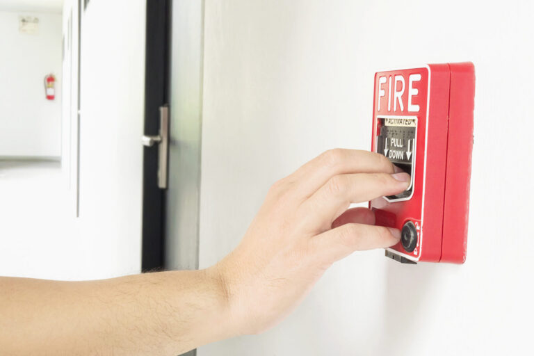 Person reaching to activate a fire alarm manual call point